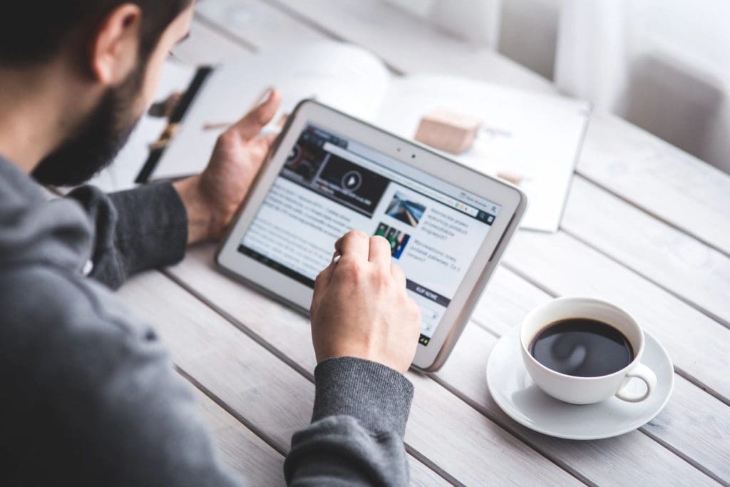 Man surfing the internet on his tablet with a cup of coffee